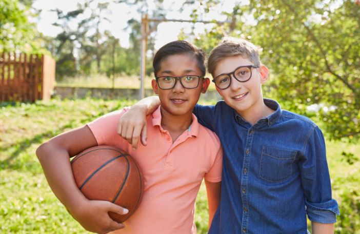 Two friends smiling at the camera while one holds a basketball.