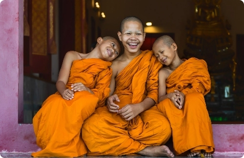3 buddhist children laughing together.