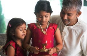 two young girls with their father practicing hindu traditions.