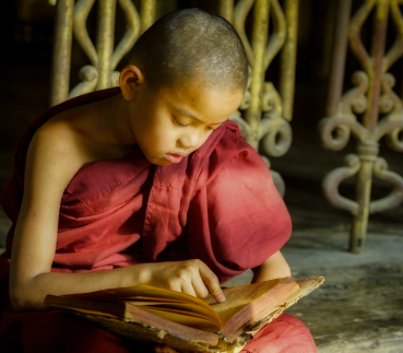 A small image of a young Buddhist child reading scriptures.